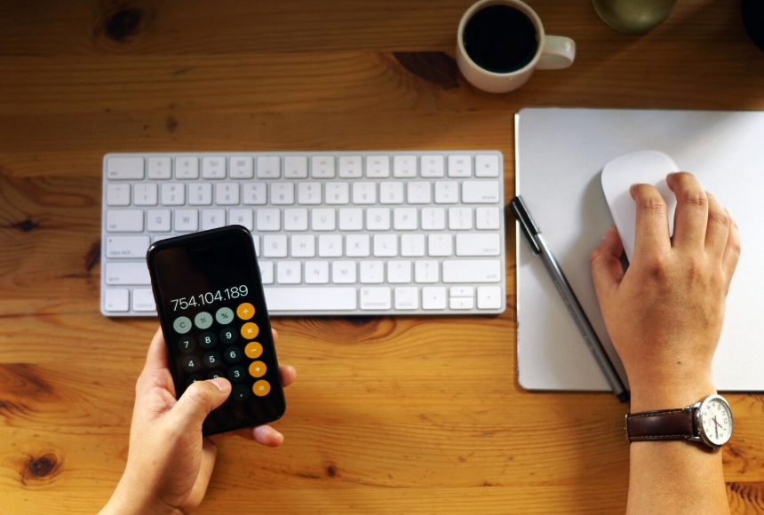 Calculator app, keyboard, notebook, and coffee used to plan a personalized streaming budget.