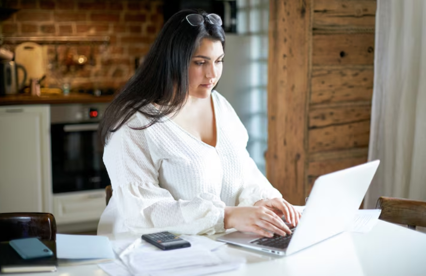 Laptop, calculator, and billing papers showing how to track streaming spending across monthly subscriptions.