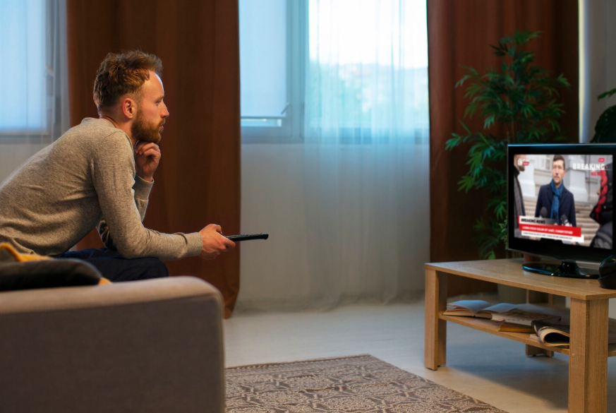 Person watching live TV at home, illustrating live TV streaming hidden fees.