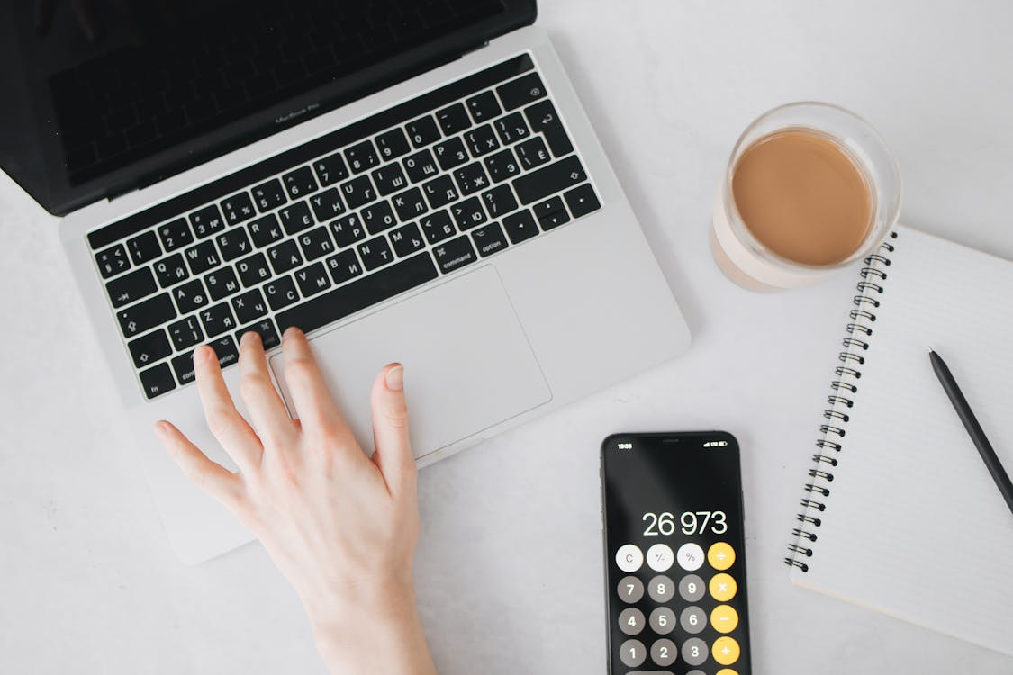 Calculator and laptop used to compare streaming cost per hour across monthly subscription services.